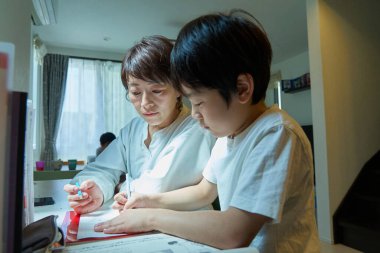 Evindeki odasında ders çalışan bir çocuk, annesi tarafından izleniyor.