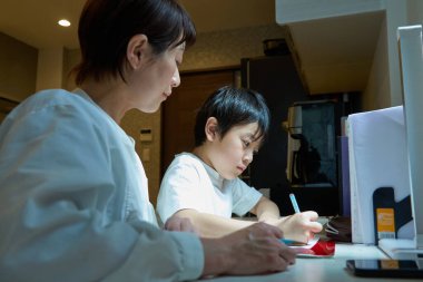 Evindeki odasında ders çalışan bir çocuk, annesi tarafından izleniyor.