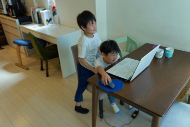 Evlerinde bilgisayar kullanan iki çocuk.