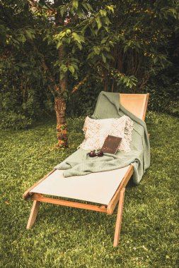 Bahçe salonu, kitap ve battaniye, dikey.