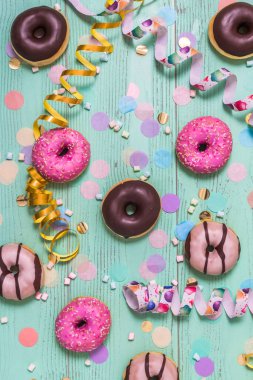 Donut, Berliner, flamalı Krapfen ve konfeti. Karnaval, doğum günü ve faşizmin renkli resmi, yeşil arka plan, üst görünüm