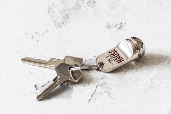 Key ring  keys with two keys and tag with German text Zu Hause (translation: at home) on a white background, copy space