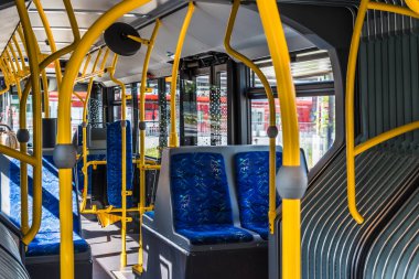 Modern bir otobüsün iç tasarımı. Otobüsün içi boş. Şehirde toplu taşıma. Yolcu taşımacılığı. Mavi koltuklu ve sarı tırabzanlı otobüs.