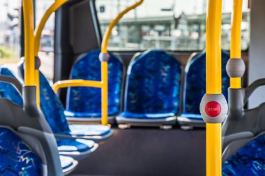 Modern toplu taşıma otobüsünün stop düğmesi. Otobüsün içi boş. Şehirde toplu taşıma. Yolcu taşımacılığı. Mavi koltuklu ve sarı tırabzanlı otobüs.