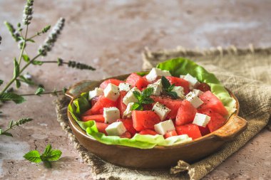 Feta peynirli taze karpuz salatası ve bej desenli arka planda nane şekeri ile süslenmiş nane şekeri.