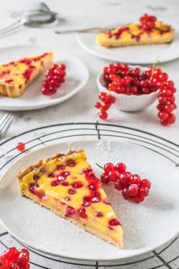 Beyaz arka planda ev yapımı kırmızı frenk üzümü turtası. Taze kırmızı üzümlerle süslenmiş, dikey.