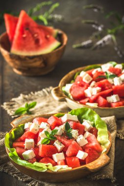 Feta peynirli taze karpuz salatası ve kırsal ahşap arka planda naneli, dikey.