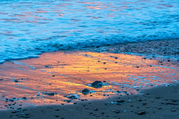Reflection of the light of the setting sun in the water on the beach.
