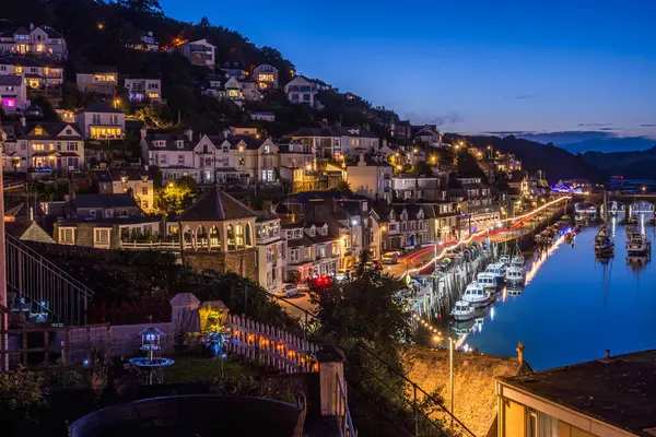 Looe, Cornwall, İngiltere - 14 Ağustos 2023: Liman ve şehir mavi saatte suya yansıyan ışıklarla 