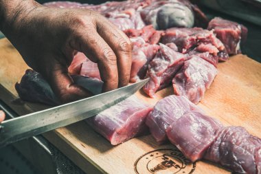 Erkek eller tahta bir tahtada eti parçalara ayırır.