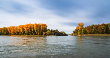 Nehir kıyısında sonbahar renkli ağaçlar, mavi gökyüzü