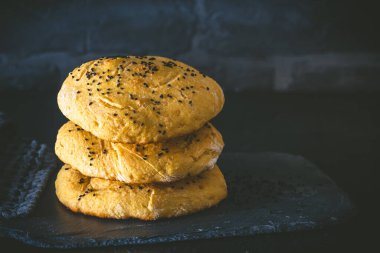 Üç ev yapımı düz ekmek, hamburger çörekleri, siyah kimyon tohumlu siyah arka plan, boşluğu kopyala