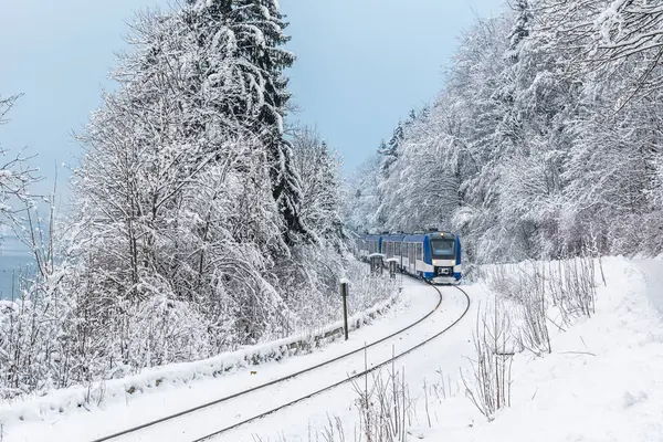 Local transport train drives through snowy landscape in Bavaria, Germany