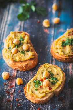 Kızarmış ekmek dilimleri, humus, nohut püresi, mavi ahşap arka planda, dikey