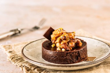 Karamelli fındık, badem ve şam fıstığı soslu çikolatalı tart.