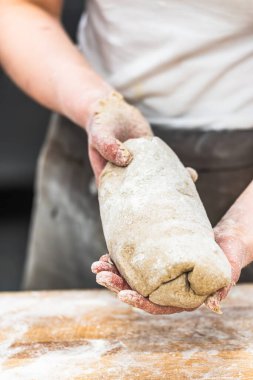 Bir fırıncı fırında ekmek hamuru hazırlıyor. Dikey.