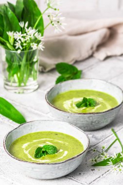 İki kase sarımsak çorbası açık gri arka planda, dikey.