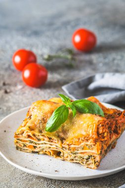 Domates soslu İtalyan lazanyası, ıspanak ve peynir, açık beton arka plan. Ev yapımı vejetaryen lazanya. Seçici odaklanma. Dikey.