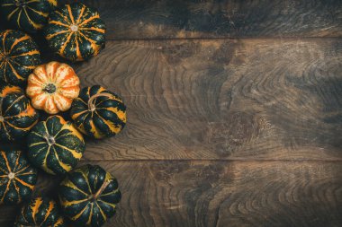 Ahşap zemin üzerinde çizgili deseni olan çeşitli küçük balkabakları, kopya alanı ile üst görünüm