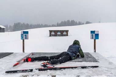 Çocuk kışın biatlon eğitimi için lazer silahıyla atış talimi yapıyor.