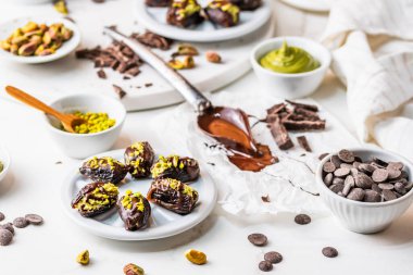 Çıtır fıstıklı krema ve çikolata kaplı, Dubai çikolatalı hurma, beyaz arka plan. Özel bir tatlı, malzemelerle düzenlenmiş..