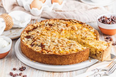 Beyaz ahşap arka planda kavrulmuş badem ve kuru üzümlü ev yapımı elmalı turta.