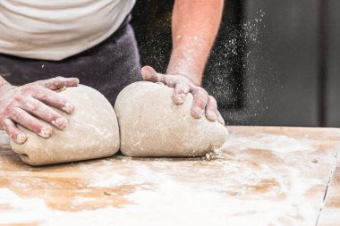 Bir fırıncı ekmek hamurunu fırında yoğurur..