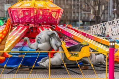 Bir panayırda çocukların girmesi için bekleyen gri bir fil.