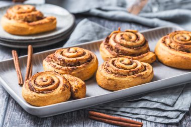 Gri arkaplanda gri bir toprak tepside ev yapımı tarçın ruloları.