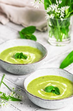 İki kase sarımsak çorbası açık gri arka planda, dikey.