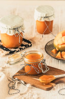 Ev yapımı mango reçeli ve beyaz ahşap masada taze mango, dikey.