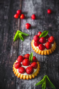 Ev yapımı çilekli turtalar, kırsal siyah ahşap masa, dikey.