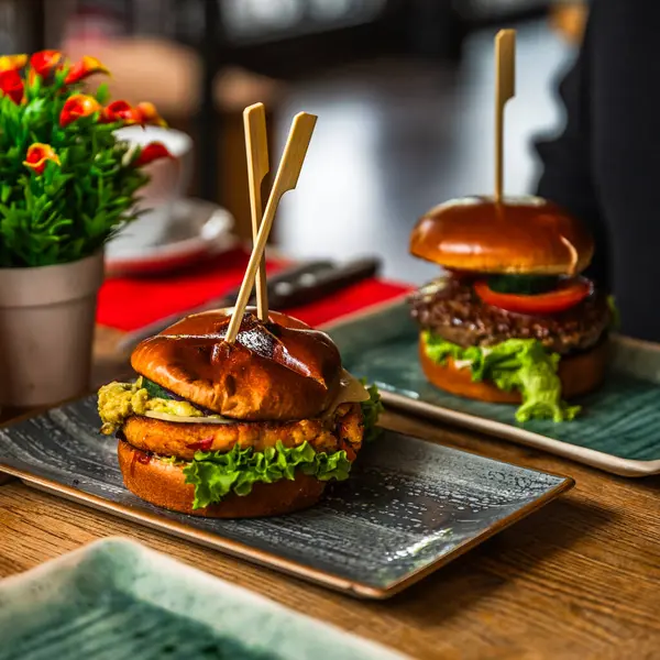 Sebze Burger bir restoranda ahşap bir masada, et burger arka planda.