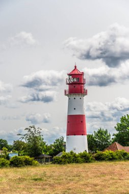 Almanya 'nın kuzeyinde Schleswig-Holstein eyâletinde, bulutlu bir günde, kırmızı ve beyaz deniz feneri Falsholeft