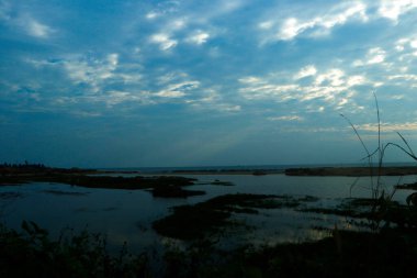 Bereketli yeşillikler ve uçsuz bucaksız mavi gökyüzü ile çevrili sakin ve huzurlu bir atmosfer yaratan sakin bir su kütlesi. Doğa, rahatlama ve çevre güzelliği kavramları için idealdir..