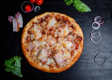 Bacon pizza, juicy and delicious.Top view of hot bacon pizzacooking ingredients tomatoes  on black background