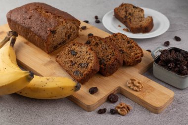 Kesme tahtasında kuru üzüm, muz, fındık ve bir dilim ekmekle birlikte bir tabak bal ekmeği. Ev yapımı konsepti..