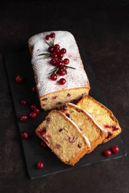 Kızılcıklı bir kekin bulanık görüntüsü, koyu arkaplandaki kesim tahtasındaki kek dilimleri. Tatlı hamur işleri.