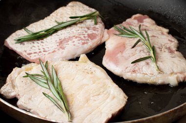 Blurred image of frying meat with butter and rosemary.