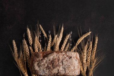 Karanlık bir arka planda, yazı ekmeği, mısır kulağı, lavanta filizi yazmak için bir yer. Ev yapımı pişirme..