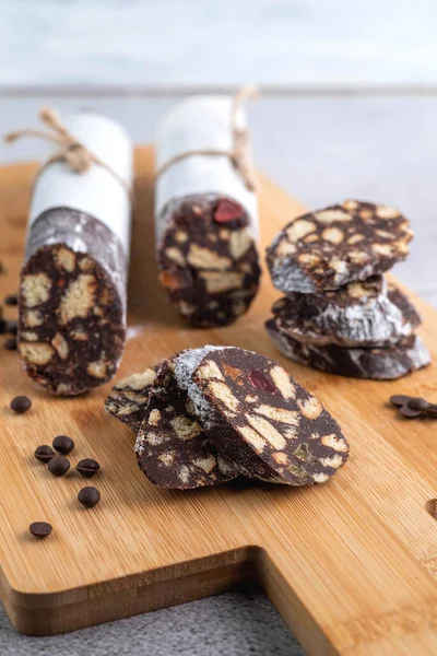 Chocolate salami on a wooden board and chocolate drops. Sweet food concept.