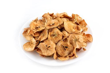 Arkaplanda beyaz bir tabakta kurumuş elma dilimleri..