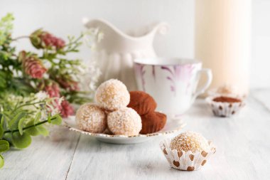 Şekerlerin bulanık görüntüsü, bir fincan kahve, yeşiller ve arka planda süt sürahisi. Kahve içme kavramı.