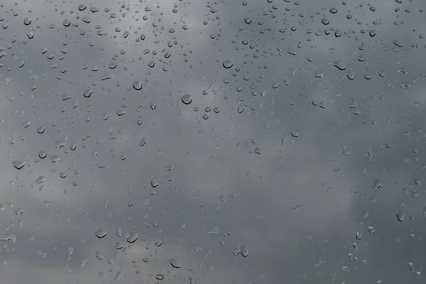 灰色の空に対してガラス上の雨滴のぼやけたイメージ — ストック写真