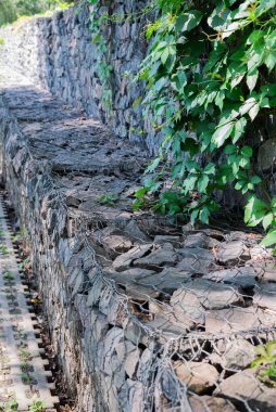 Vahşi üzümlerle kaplı taş bir Gabion 'un bulanık görüntüsü..