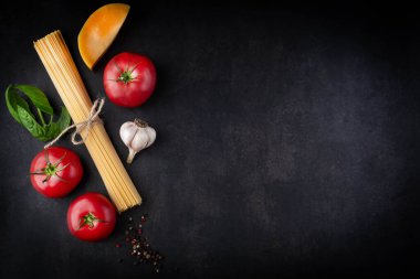 Spagetti, domates, peynir, fesleğen, baharat ve sarımsak. Arka planda mesaj yazmak için yer var. Yemek pişirme kavramı..