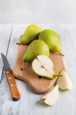 Ahşap bir tahtada armutlar ve ışık masasında bir bıçak.