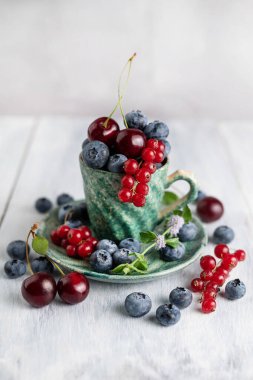 Yaban mersini, kırmızı frenk üzümü, yeşil seramik fonda kiraz. Yaz hala hayat.