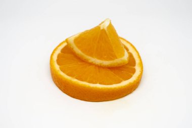 An orange slice and a quarter standing on top of it on a white background