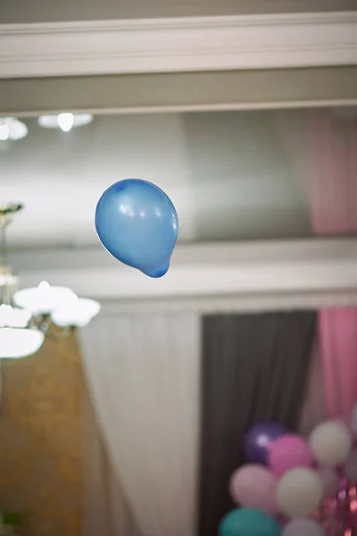Vertical shot of a blue inflatable ball flying in the air in a room